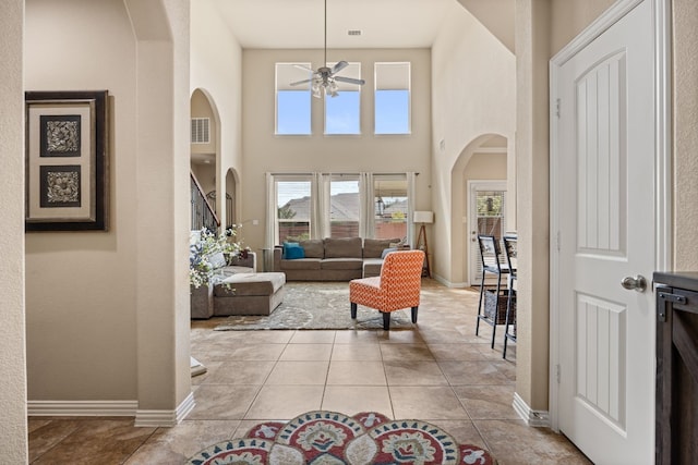 interior space featuring a ceiling fan, baseboards, visible vents, and arched walkways