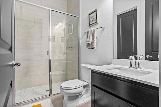 full bathroom with a stall shower, a textured wall, vanity, and toilet