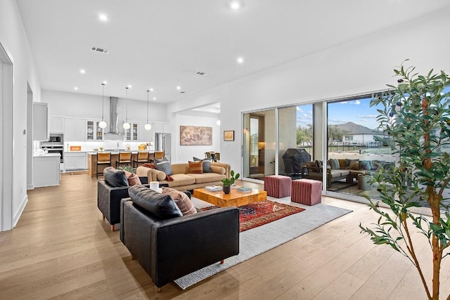 living area with light wood-type flooring, visible vents, and recessed lighting