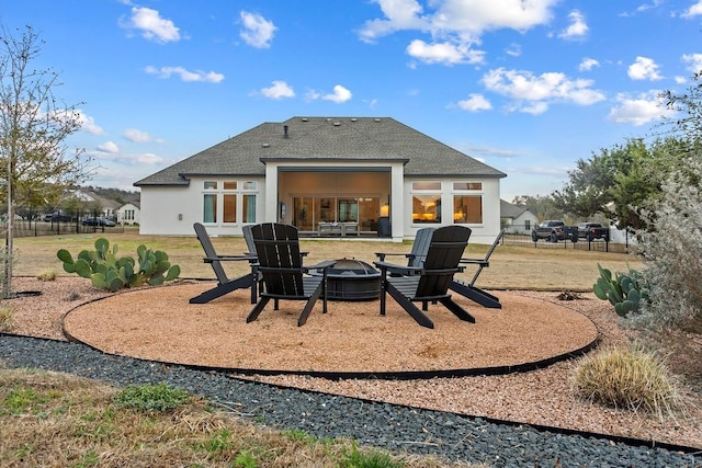 rear view of house featuring roof with shingles, a patio, stucco siding, fence, and a fire pit