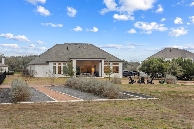 back of property featuring stucco siding, a lawn, and fence