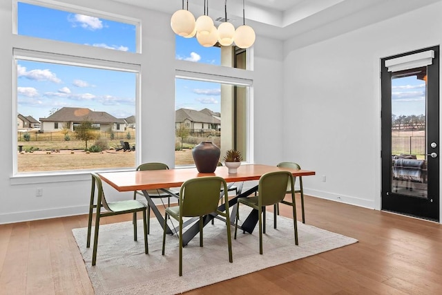 dining room with baseboards, wood finished floors, a wealth of natural light, and a notable chandelier