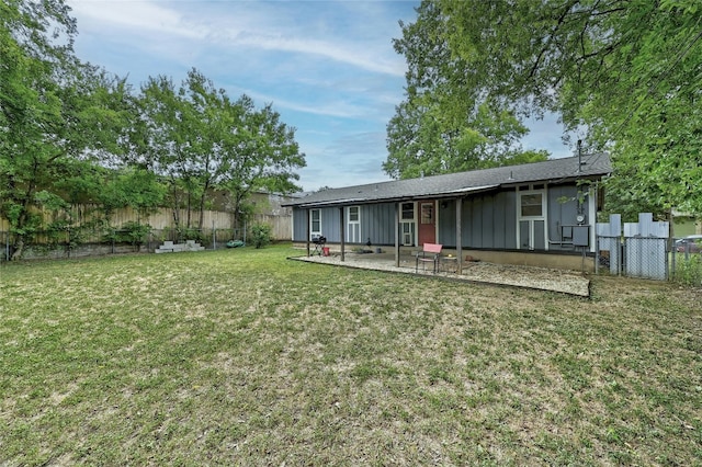 back of house featuring board and batten siding, a patio area, a fenced backyard, and a lawn