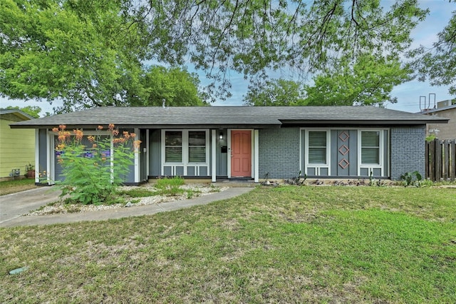 view of front facade featuring brick siding, fence, a garage, driveway, and a front lawn