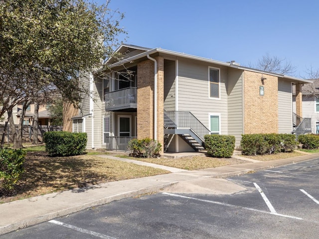 view of property featuring uncovered parking, fence, and stairway