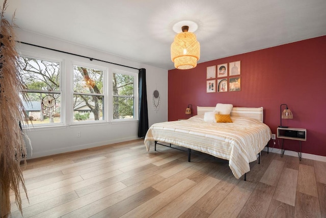 bedroom featuring light wood finished floors and baseboards