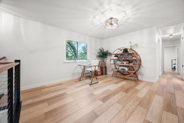 home office with attic access, light wood-type flooring, and baseboards