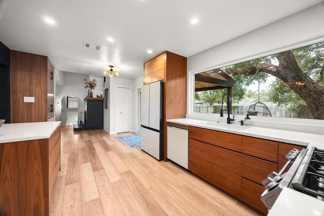 kitchen with white appliances, modern cabinets, brown cabinets, and a sink