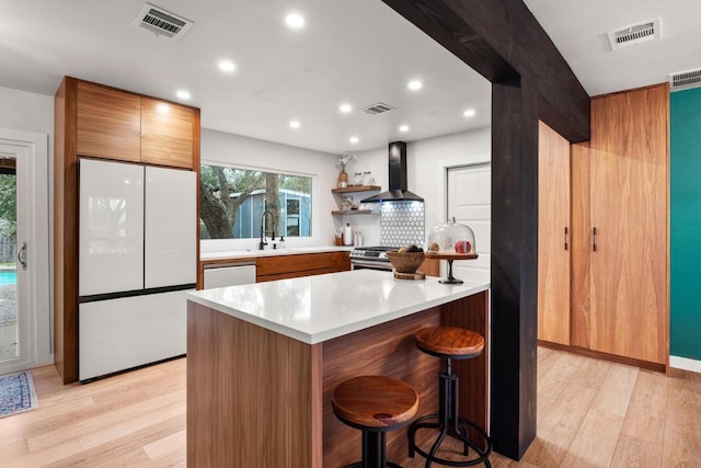 kitchen with visible vents, light countertops, wall chimney range hood, and white appliances