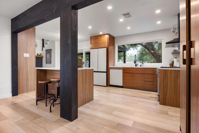 kitchen with white appliances, modern cabinets, visible vents, and brown cabinets