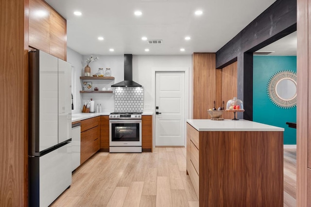 kitchen featuring white appliances, light wood-style flooring, modern cabinets, light countertops, and wall chimney range hood