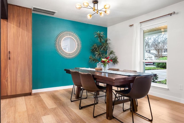 dining room with visible vents, a notable chandelier, light wood-style flooring, and baseboards