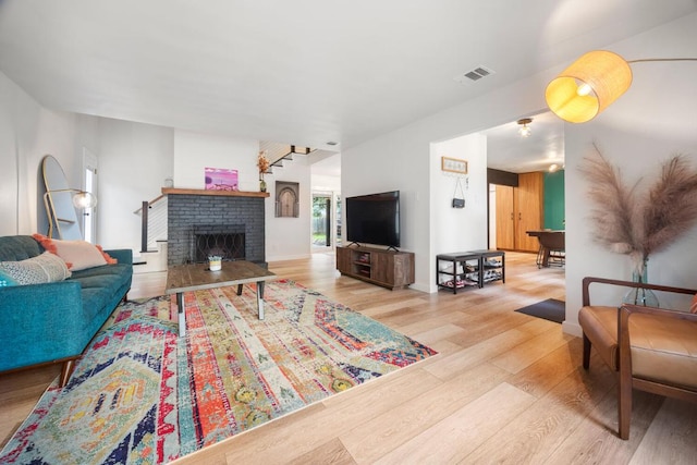 living area featuring baseboards, a fireplace, visible vents, and wood finished floors