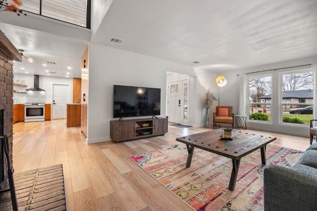 living room featuring light wood finished floors, baseboards, a fireplace, and visible vents