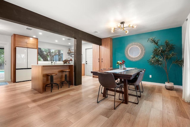 dining space with visible vents, an inviting chandelier, an accent wall, light wood-style floors, and baseboards