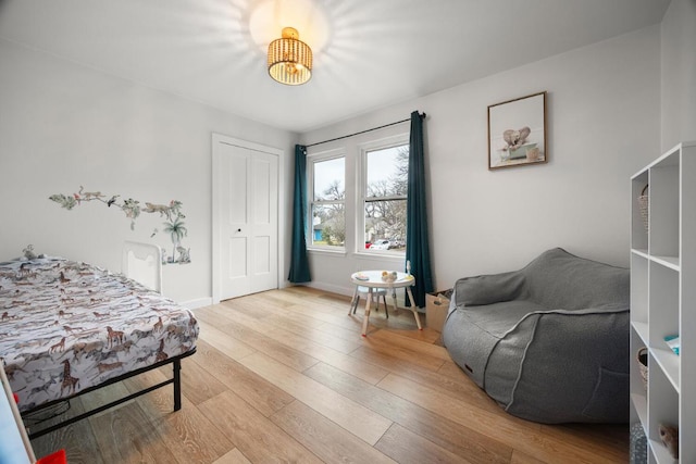 bedroom with light wood-style flooring, baseboards, and a closet