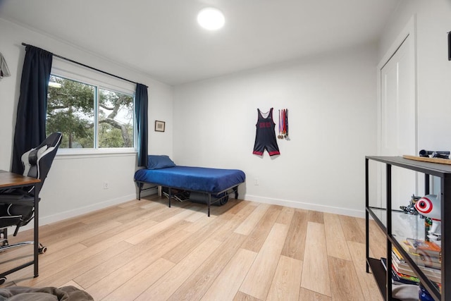 bedroom featuring light wood finished floors and baseboards