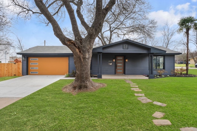 mid-century home featuring a garage, fence, concrete driveway, and a front yard