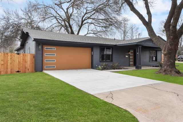 view of front facade with an attached garage, a shingled roof, fence, concrete driveway, and a front lawn