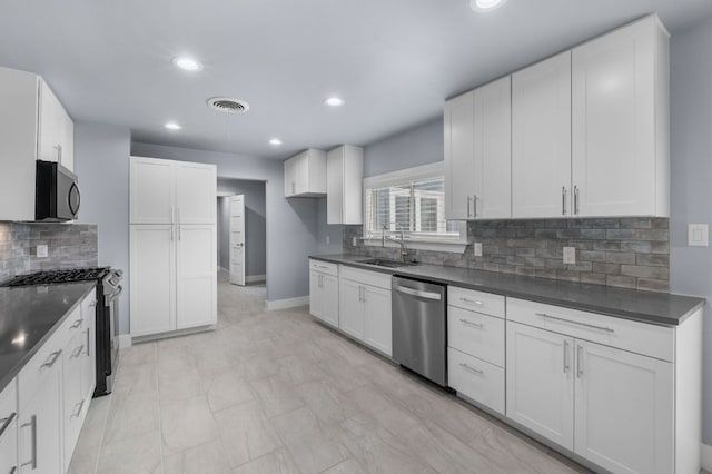 kitchen with dark countertops, recessed lighting, visible vents, appliances with stainless steel finishes, and a sink