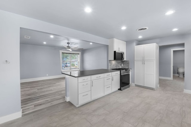 kitchen with visible vents, dark countertops, appliances with stainless steel finishes, white cabinetry, and backsplash