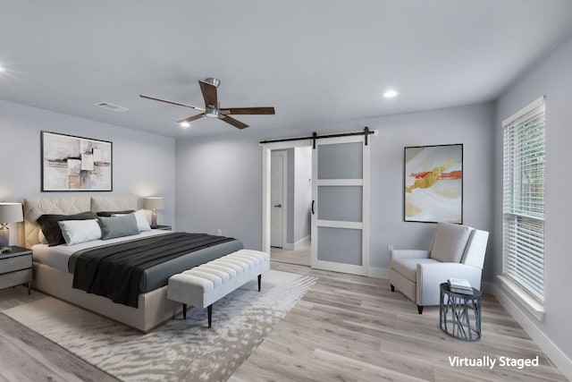 bedroom featuring recessed lighting, visible vents, a barn door, light wood-type flooring, and baseboards