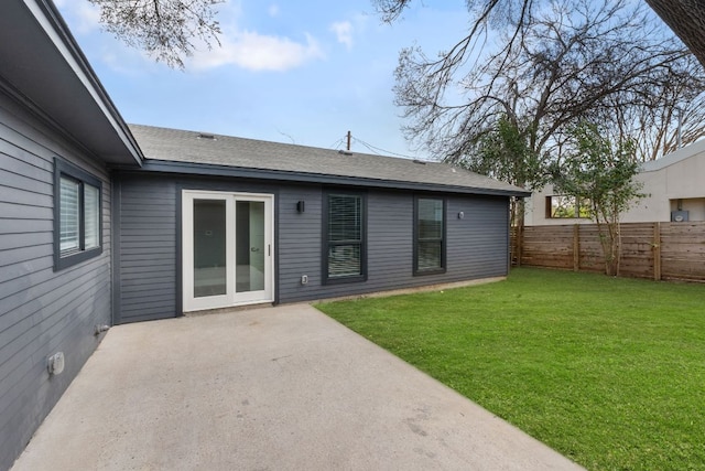 rear view of property featuring a yard, roof with shingles, a patio, and fence