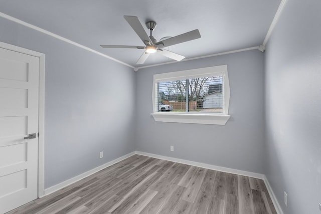 unfurnished room with crown molding, baseboards, and wood finished floors