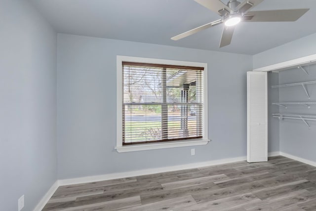 unfurnished bedroom featuring ceiling fan, a closet, wood finished floors, and baseboards