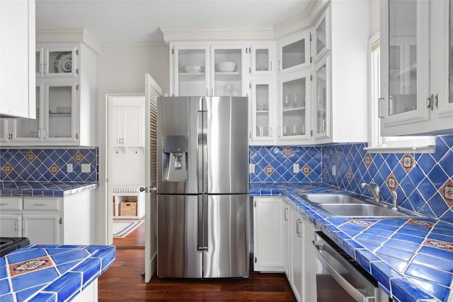 kitchen with stainless steel appliances, white cabinetry, and tile countertops