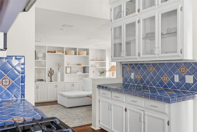 kitchen with glass insert cabinets, white cabinetry, tile countertops, and decorative backsplash