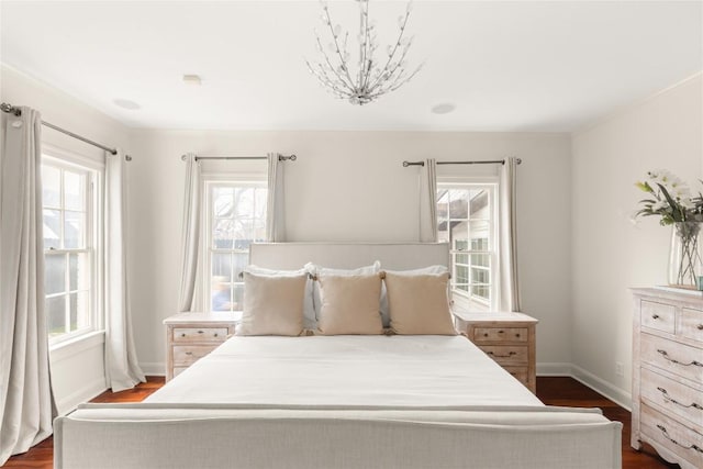 bedroom with dark wood-style floors, multiple windows, and baseboards