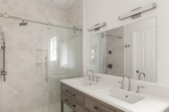 bathroom with a sink, a shower stall, and double vanity