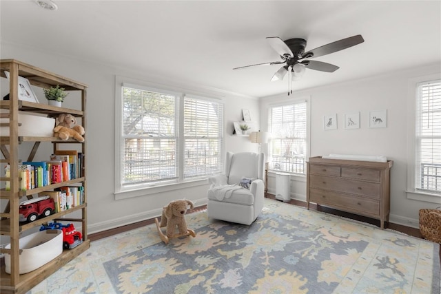 sitting room with a ceiling fan, a healthy amount of sunlight, baseboards, and wood finished floors