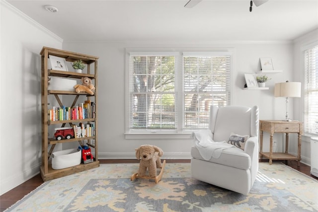 sitting room featuring crown molding, plenty of natural light, baseboards, and wood finished floors