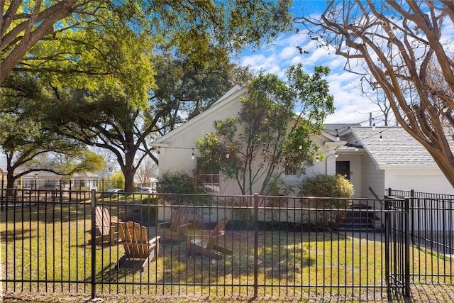 view of side of home featuring a shingled roof, a lawn, an attached garage, and fence