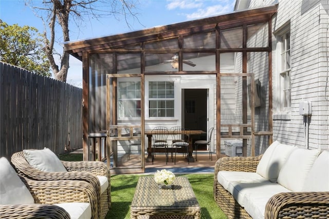 view of patio / terrace with a sunroom, outdoor dining area, fence, and an outdoor living space