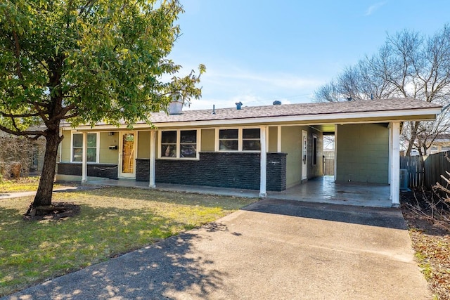 ranch-style home with fence, concrete driveway, stone siding, a carport, and a front yard