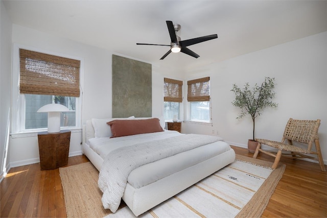 bedroom featuring a ceiling fan, baseboards, and wood finished floors