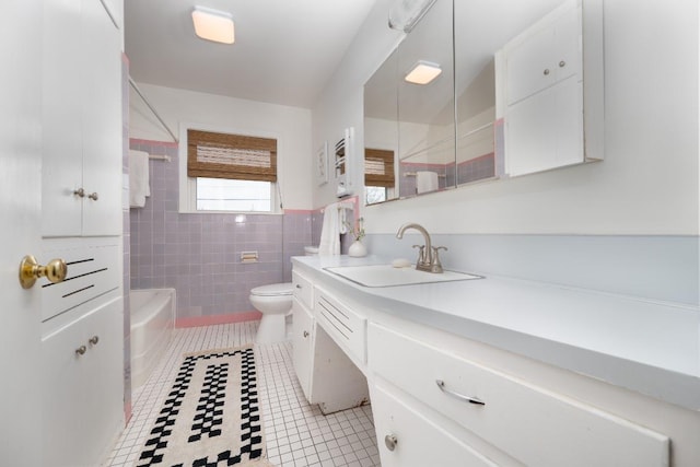 bathroom with toilet, vanity, tile patterned flooring, and tile walls