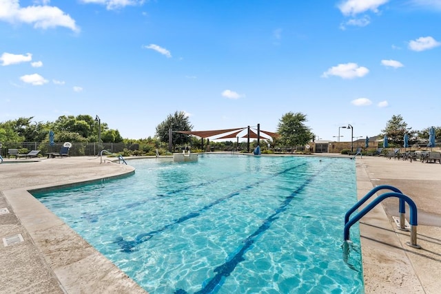 pool featuring a water slide, a patio area, and fence