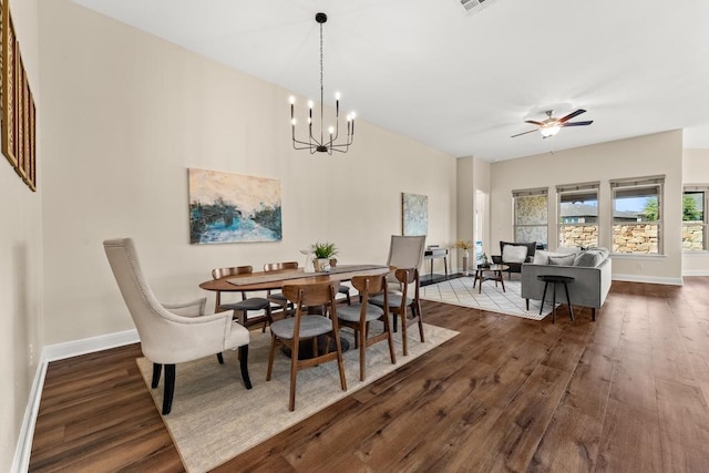 dining room featuring ceiling fan with notable chandelier, dark wood-type flooring, and baseboards