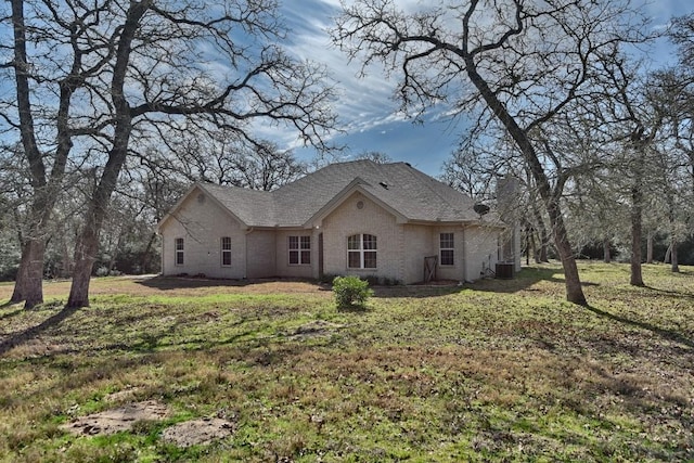 view of property exterior featuring brick siding, a shingled roof, a yard, and cooling unit