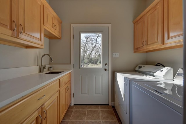 laundry area featuring dark tile patterned flooring, washer and clothes dryer, a sink, and cabinet space