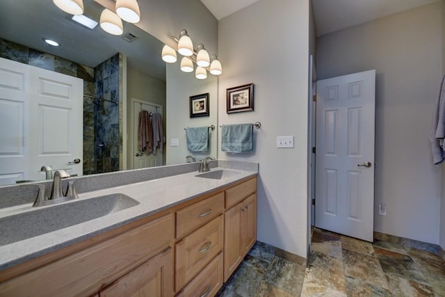 bathroom with double vanity, stone finish floor, a sink, and tiled shower