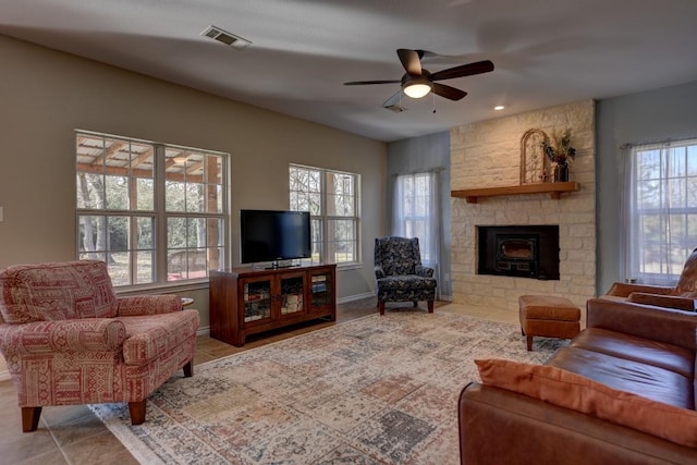 tiled living area featuring a healthy amount of sunlight, a fireplace, visible vents, and a ceiling fan