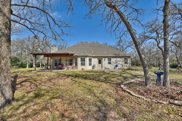 back of house featuring a patio area, a chimney, and a lawn