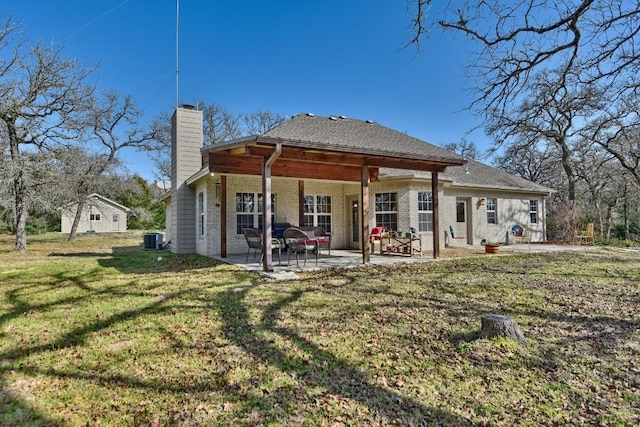 rear view of property with a patio, cooling unit, brick siding, a lawn, and a chimney