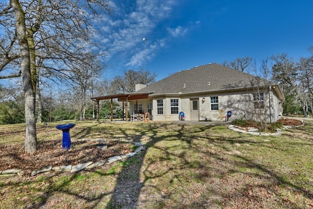 back of house featuring a patio area, a chimney, and a yard