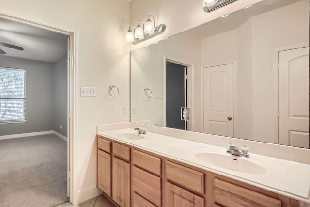 bathroom with double vanity, ceiling fan, baseboards, and a sink